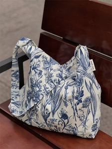 Floral canvas tote bag with blue botanical pattern and white label on a wooden bench