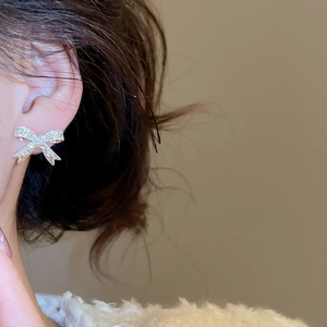 Gros plan de boucles d'oreilles nœud argentées avec zircons sur un mannequin en fourrure