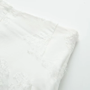 Gros plan détaillé montrant les franges blanches et la texture de l'ensemble jupe