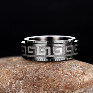 Macro detail of rotating stainless steel ring with Greek meander pattern and brushed finish