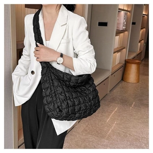 Detailed view of black quilted puffer tote bag on shoulder with sleek nylon texture
