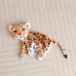 Close-up of soft snow leopard plush fabric with realistic spots and yellow eyes