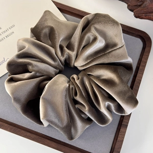 Detail of coffee brown velvet scrunchie showing rich fabric texture on wooden tray