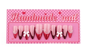 Macro view of burgundy French tip press-on nails with 3D white bows and pearls on M-size card