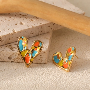 Detail of heart-shaped gold studs with colorful enamel drip art on stone background