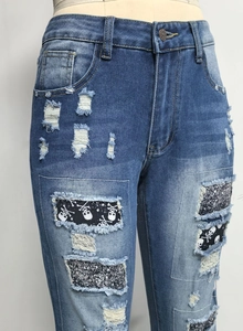 Detail von zerrissenen Jeans mit Totenkopf-Patches, Glitzerakzenten und Denim-Textur