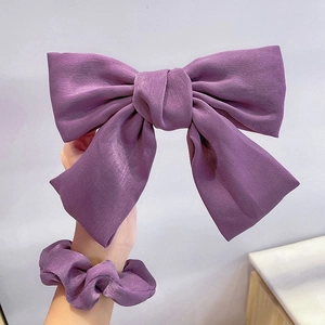 Close-up of purple satin hair accessories set featuring bow clip and scrunchie detail