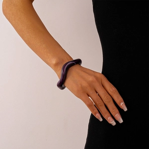 Detail of a deep purple wavy acrylic resin bangle with a smooth polished glossy finish