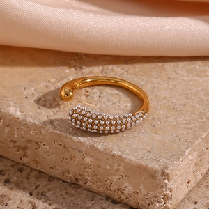 Detailed macro view of a gold open ring with micro-pave white pearls on a stone base