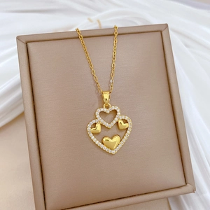 Elegant gold double heart necklace with sparkling crystals on a beige jewelry box