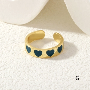 Detailed close-up of golden adjustable heart ring with blue enamel dripping oil craft