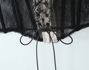 Close-up of black lace corset with beige mesh lining and criss-cross tie-up detail