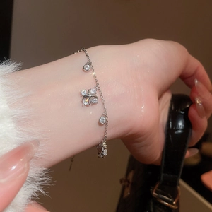 Detail of silver clover zircon bracelet on wrist with elegant lifestyle background