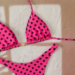 Detailed close-up of pink polka dot bikini top with a golden sun metal buckle detail