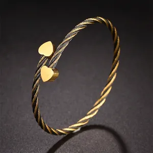 Détail du bracelet torsadé en acier titane avec breloques dorées en forme de cœur