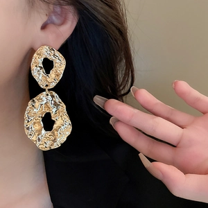 Close-up of vintage irregular gold geometric earrings with textured metallic finish