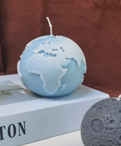 Artistic detail of 3D earth and moon scented candles on a white book display base