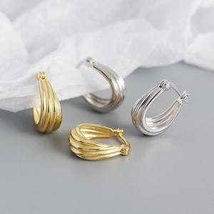 Macro shot of gold and silver S925 sterling silver hoop earrings with vertical stripe texture