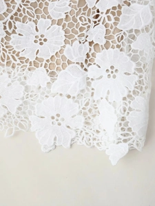 Détails de broderie florale en dentelle blanche et texture de maille ajourée raffinée