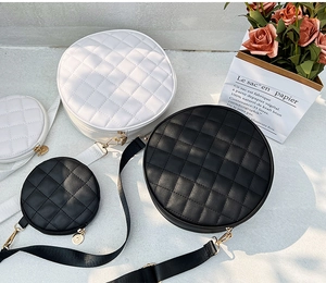 Detail of round quilted shoulder bags in black and white with gold hardware