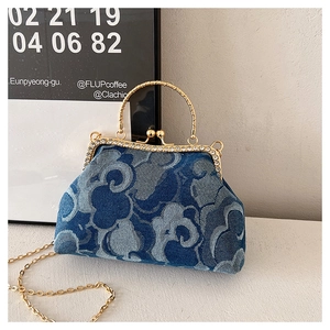 Detail of blue denim handbag featuring floral print, gold metal frame and diamond clasp