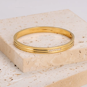Elegant gold stainless steel bangle featuring delicate grooves and cubic zirconia inlay