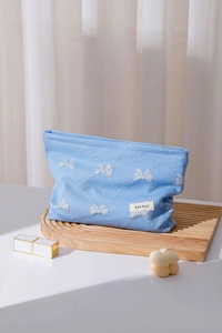 Dettaglio della trousse celeste con ricami a farfalla bianchi ed etichetta sul vassoio