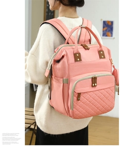 Detailed view of the pink multi-functional diaper bag being worn in a lifestyle setting