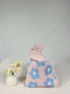 Detail of light pink knitted flower handbag with blue floral pattern and soft texture