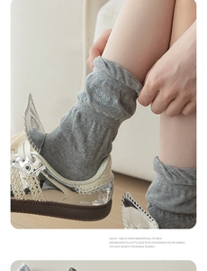 Detail of grey slouch socks with blue embroidery and stylish silver sneakers with mesh