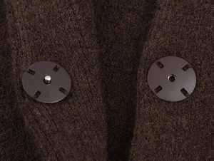 Close-up of dark brown chunky knit fabric with black metal snap button closure