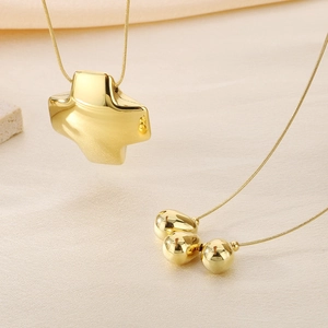 Detailed shot of two gold-plated necklaces with cross pendant and polished beads on snake chains