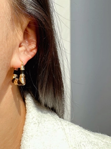 Close-up of black and gold zebra texture earrings worn on ear with natural lighting