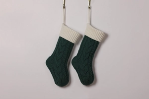 Detailed view of green knitted Christmas stockings with white cuffs and thick cable texture