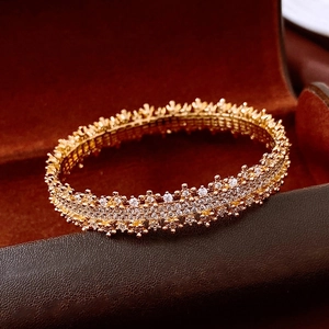 Close-up of 18k gold plated bangle with pavé zircon crystals on luxury red velvet