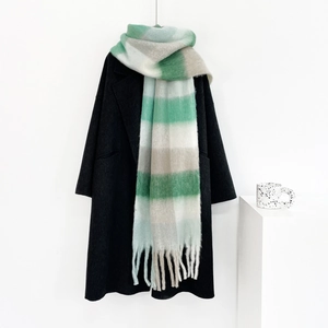 Detail of soft mohair green plaid scarf with fringe on black coat with a ceramic cup