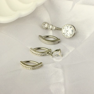 Detailed view of silver stainless steel navel rings set with clear zircon on white silk