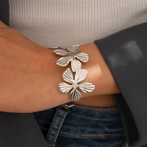 Dettaglio di bracciale a polsino con fiore d'argento su modella con petali pieghettati