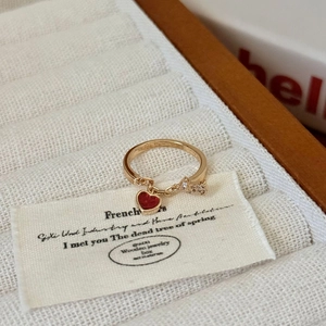 Bague dorée en gros plan avec cœur rouge et pendentif fleur brillante en écrin à bijoux