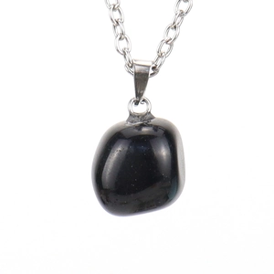 Detailed view of an irregular polished black stone pendant with a silver metal chain