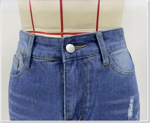 Dettaglio della gonna di jeans a vita alta con bottone metallico e bordi strappati