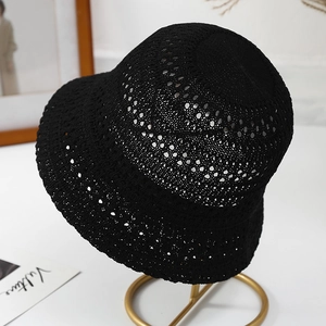 Detailed macro view of black hollow-out crochet bucket hat with intricate knit texture