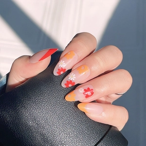 Almond-shaped press-on nails featuring red French tips and orange daisy floral patterns