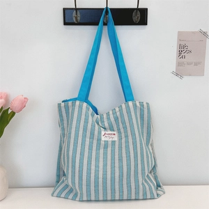 Dettaglio della borsa tote in tela a righe blu e bianche con etichetta SOZAKKA e manico