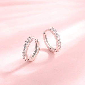 Sparkling S925 sterling silver hoop earrings with white zircon on pink silk background