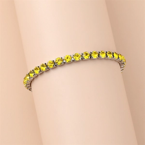 Detailed close-up of a silver tennis bracelet featuring vibrant yellow round-cut crystals
