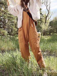 Detail of loose fit orange overalls featuring functional cargo pockets and zipper design