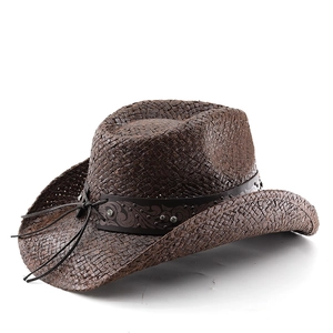 Detail of western straw cowboy hat with rhinestone studded leather belt and vintage pattern