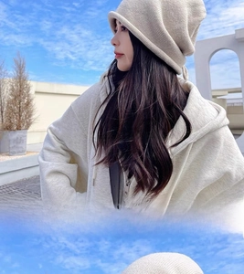 Detail view of cream white knit beanie showing rolled edge and decorative drawstring