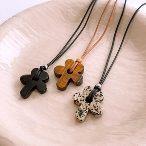 Detailed view of handmade flower pendants in tiger eye and onyx on wax cord necklaces